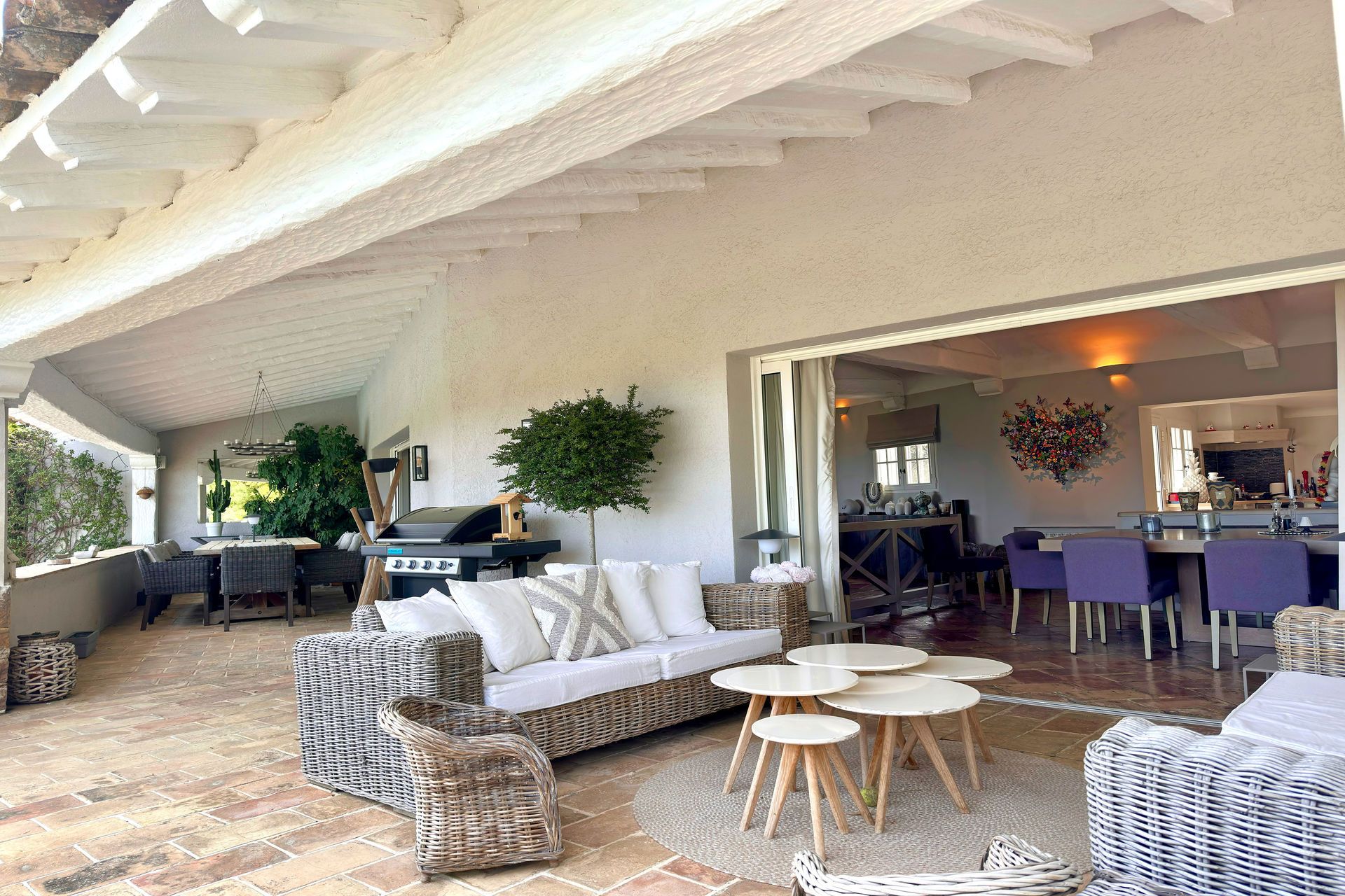 Terrasse couverte avec salon en rotin ouverte sur la salle à manger