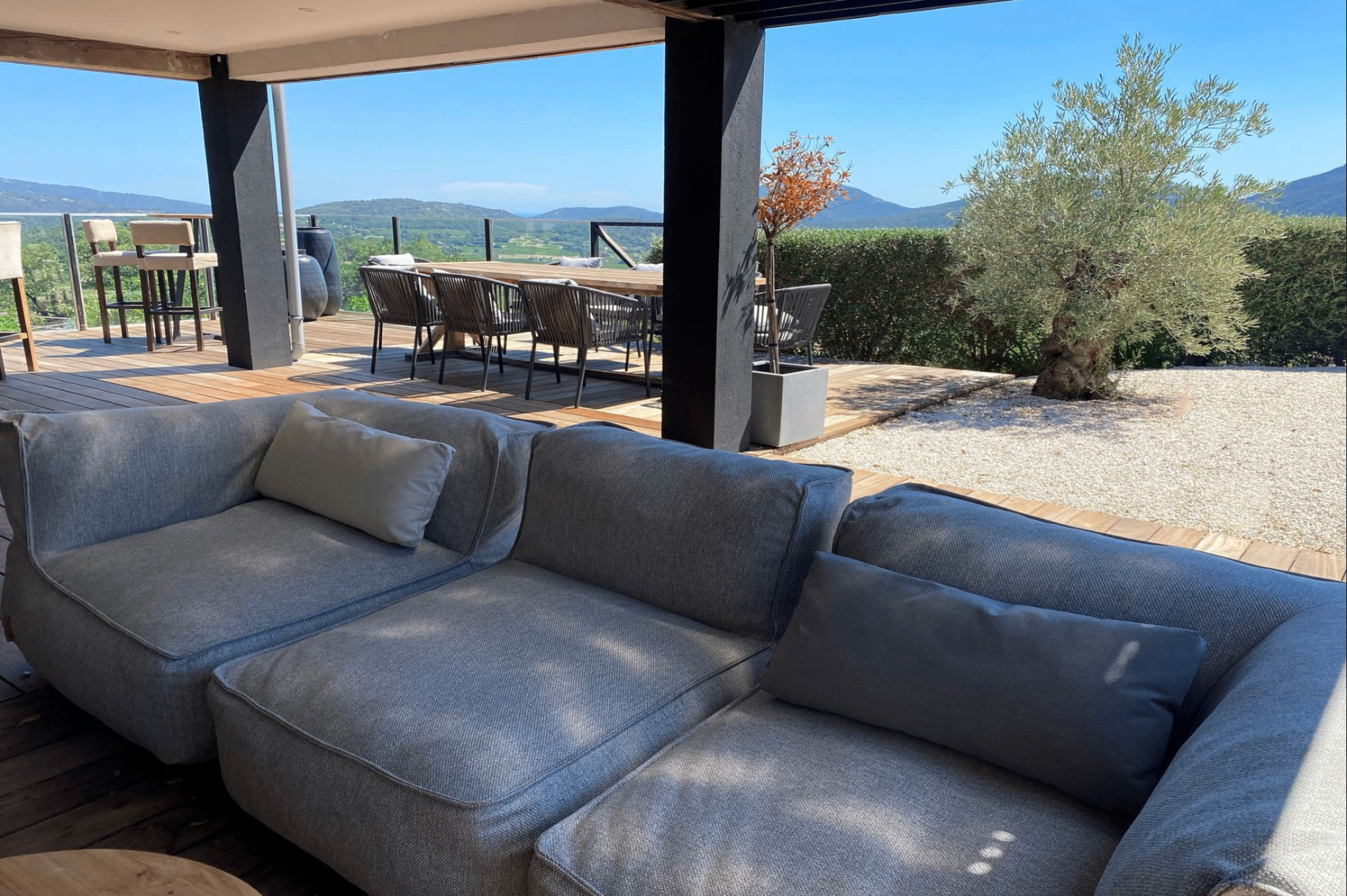 Pool house — salon lounge en lin gris et table à manger sous pergola, vue sur les collines